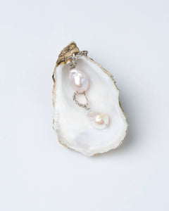 A pair of white baroque pearl earrings with silver-tone chain latch-back clasps.