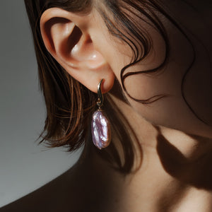 Close-up editorial of pink lavender baroque pearl earring with gold hook — Mayfair Pearls jewellery