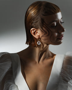 Woman is wearing a pair of gold baroque white pearl earrings with latch-back clasps. Perfect for office fit. 