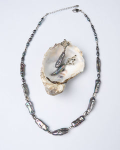 Dark iridescent baroque pearl necklace with matching drop earrings, displayed in oyster shell — Mayfair Pearls jewellery set