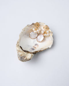 A pair of gold-tone floral stud earrings with small green rhinestone accents, suspending a cluster of freshwater pearls, with a baroque pearl serving as the coin-shaped centerpiece.