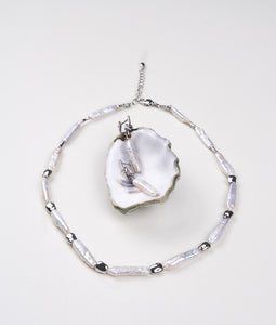 A short necklace of shimmering white stick pearls with silver accents and a pair of matching latch-back earrings.