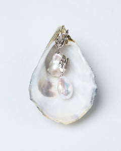A pair of silver leaf white baroque earrings with cubic zirconia placed on a natural pearl, set against a white background. Mayfair Pearls anniversary gift earrings.
