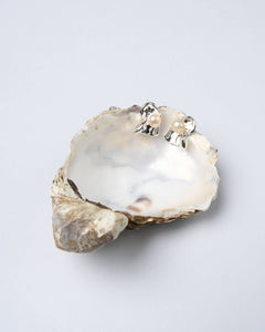 A pair of sculpted wave pearl stud earrings with a silver-tone backdrop and lustrous freshwater pearls.